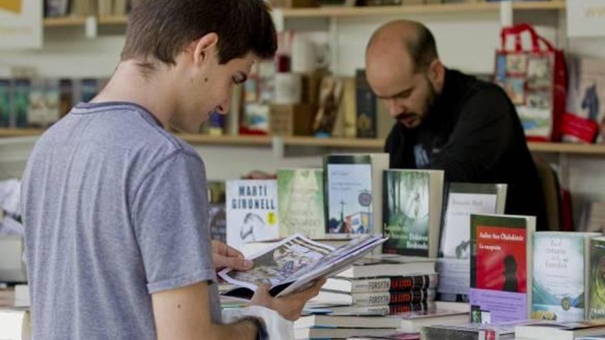 Un joven visita una caseta de la Fira del Llibre de Valencia.