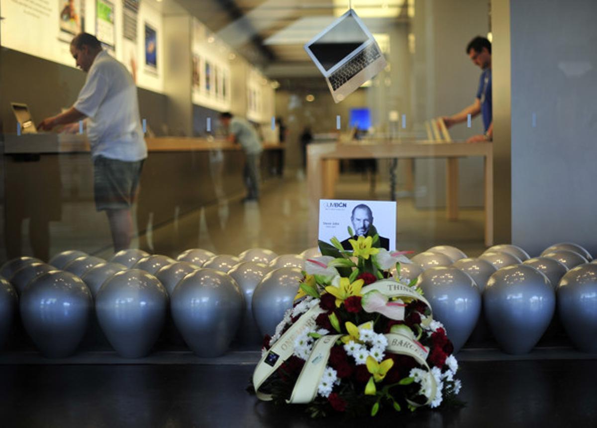 Un ram de flors al costat d’una fotografia de Steve Jobs davant de l’Apple Store de Barcelona.