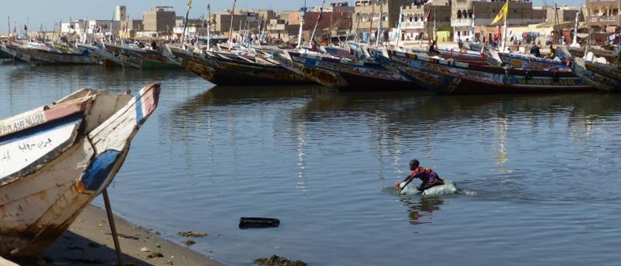 Un niño juega en el mar entre los cayucos de la localidad pesquera de Saint Louis, en Senegal. | ANGELES LUCAS