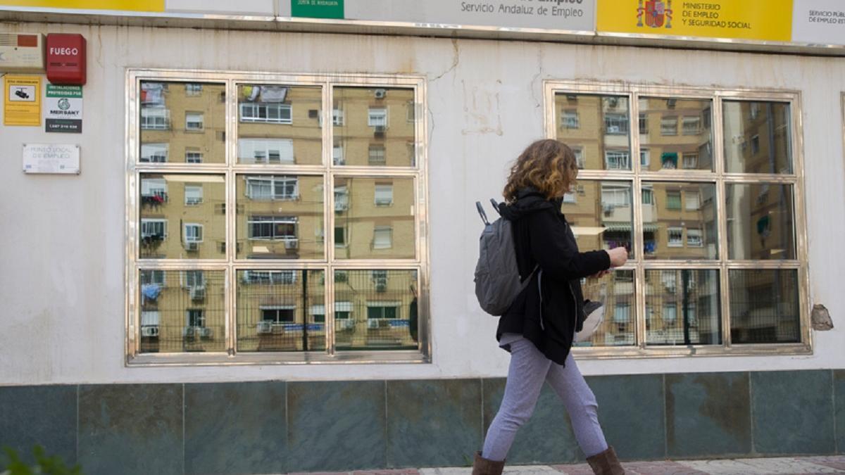 Una mujer delante de una oficina de empleo.