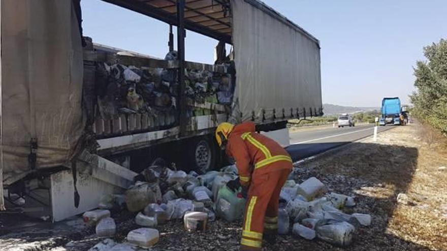 Un bombero maneja la mercancía incendiada, ayer en la autovía.