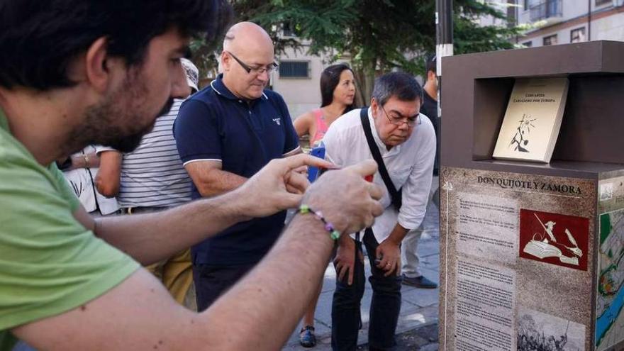 Un grupo de curiosos lee y fotografía el monolito descubierto en la plaza de los Ciento.