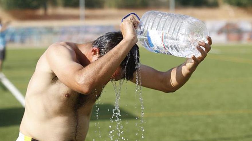 Un hombre se refresca del intenso calor con una garrafa de agua.