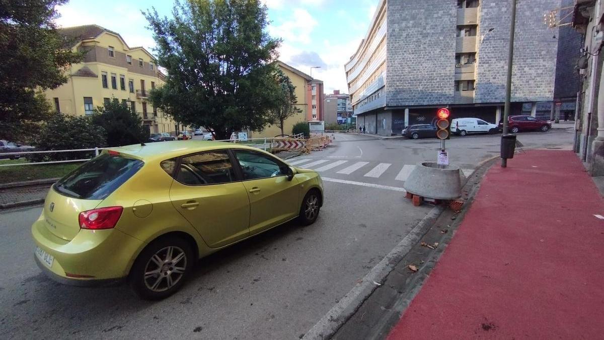 Un semáforo regulando el tráfico con la obra al fondo.