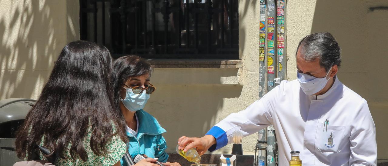 Archivo - Un camarero sirve un refresco a dos personas en una terraza