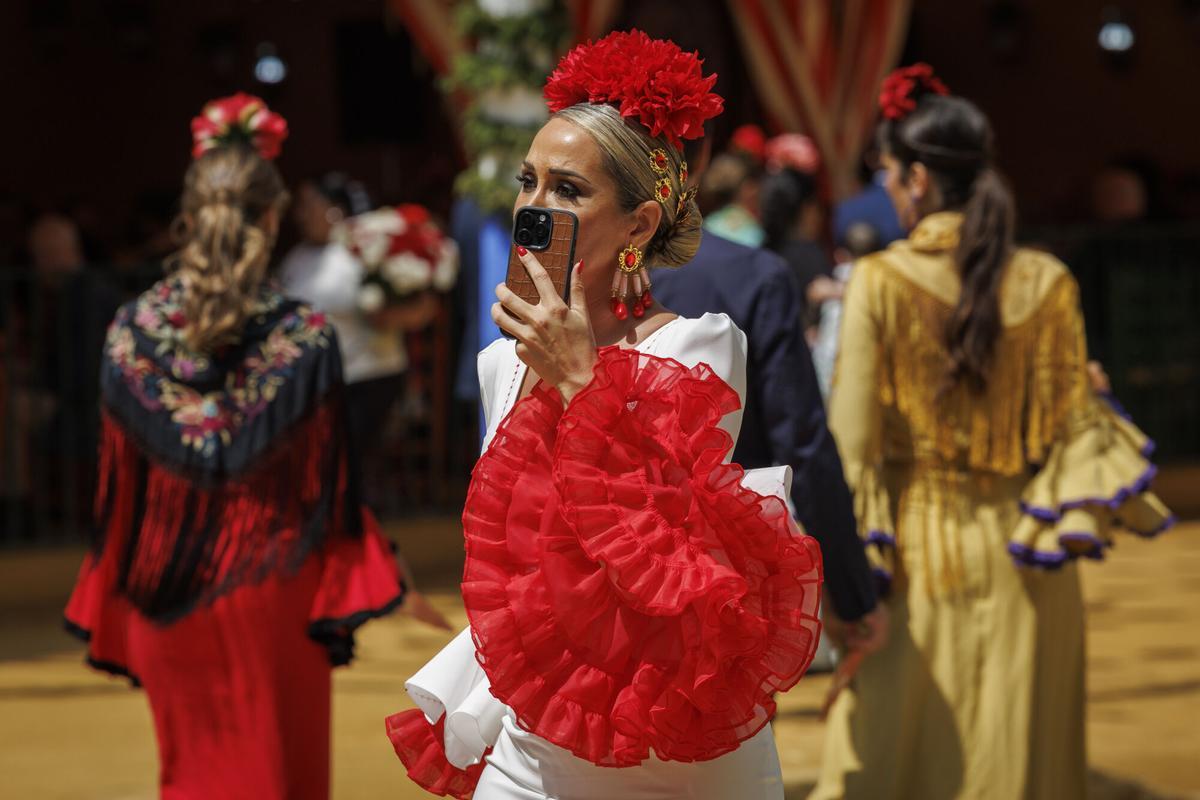 Una mujer vestida de flamenca pasea con temperaturas primaverales por las calle del Real de la Feria de Abril de Sevilla hoy miércoles, festivo local para los sevillanos.
