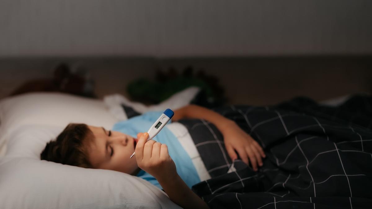 Un niño enfermo espera a que el termómetro mida su temperatura.