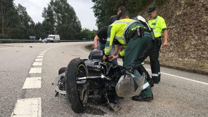 La moto en la que viajaba el motorista fallecido; al fondo, la zona en la que impactó contra el firme.