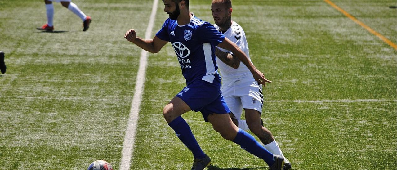 Fuli, de la UD San Fernando, conduce un balón perseguido por Agoney González, grancanario de la SD Tenisca.