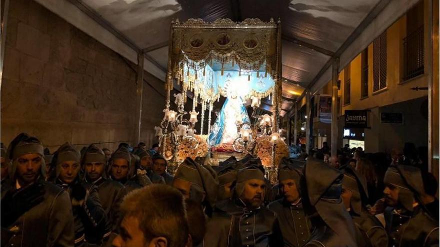 La Virgen y sus cofrades, protegidos de la lluvia en una carpa.