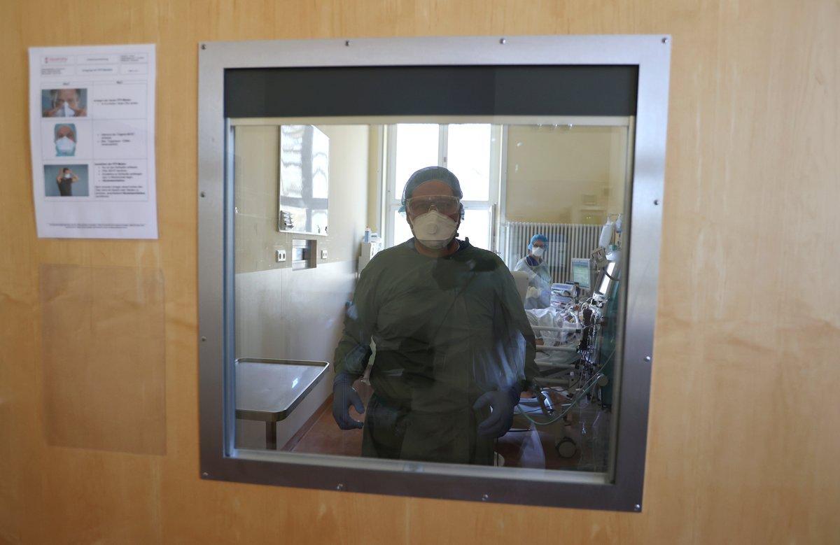 A member of the medical staff is seen through the door while treating a patient suffering from the coronavirus disease (COVID-19) in an intensive care unit at Havelhoehe community hospital in Berlin, Germany, April 6, 2020. REUTERS/Fabrizio Bensch