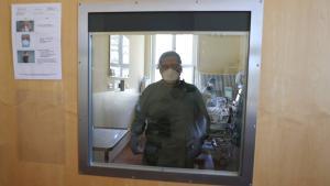A member of the medical staff is seen through the door while treating a patient suffering from the coronavirus disease (COVID-19) in an intensive care unit at Havelhoehe community hospital in Berlin, Germany, April 6, 2020. REUTERS/Fabrizio Bensch