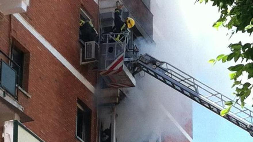 Un bombero accede a la ventana de uno de los domicilios afectados por el incendio.