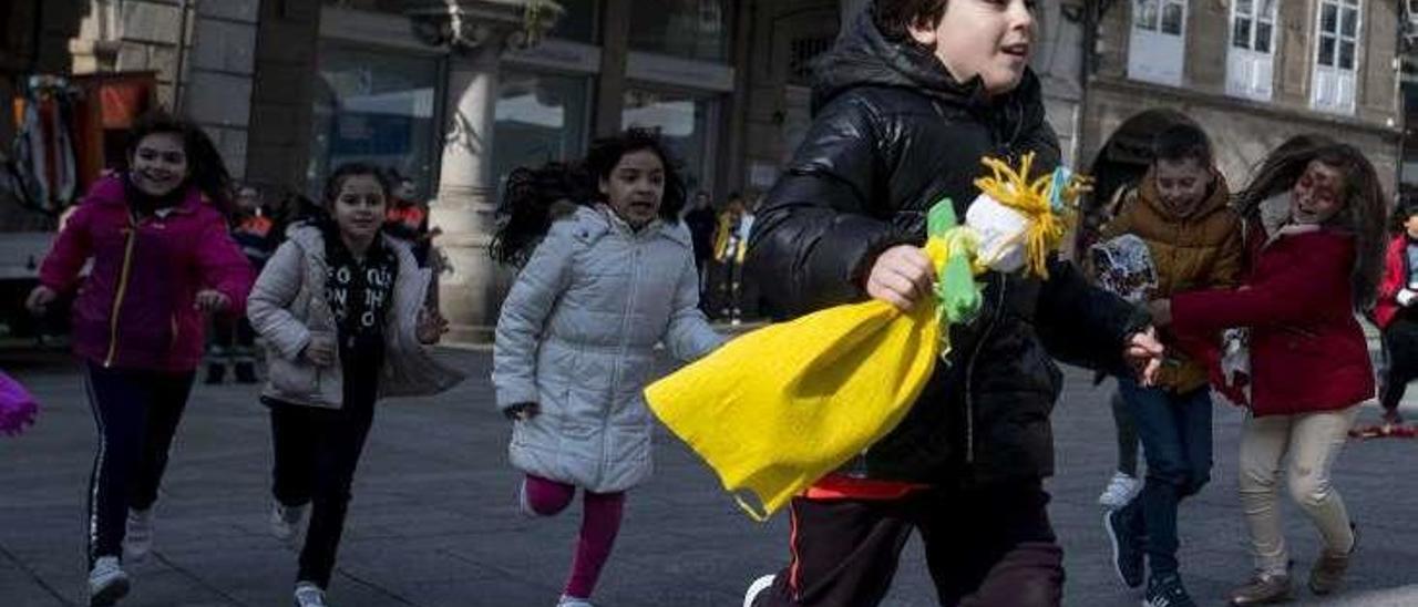 Un niño corre ante la presencia de tres niñas en la Plaza Mayor. // Brais Lorenzo