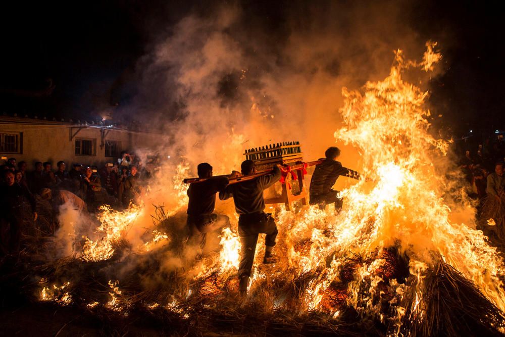 Unos hombres saltan sobre un fuego para atraer la buena suerte en un ritual tradicional por el año lunar nuevo chino.