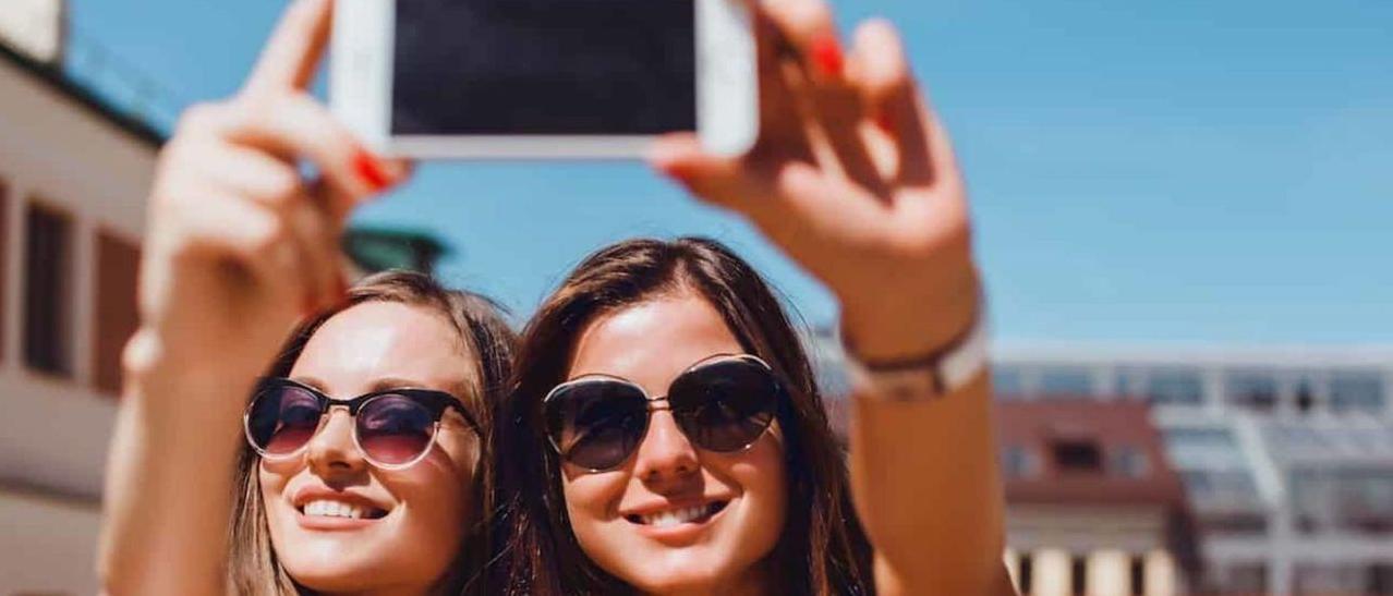 Dos jóvenes, haciéndose un selfi durante un viaje.