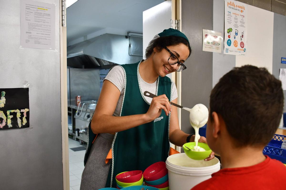 Una monitora reparte el yogur de postre a un alumno del colegio público Rossend Montané, de Sant Pere Molanta, en Olèrdola (Alt Penedès).