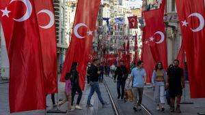 Ciudadanos de Estambul caminan por la avenida Itiklak, decorada con banderas de Turquía para conmemorar el centenario del país.