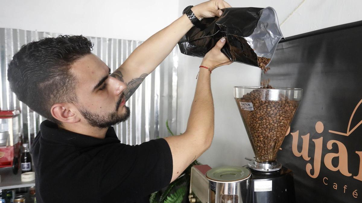 Un chico vierte café en grano en una cafetera de Medellín, en Colombia.