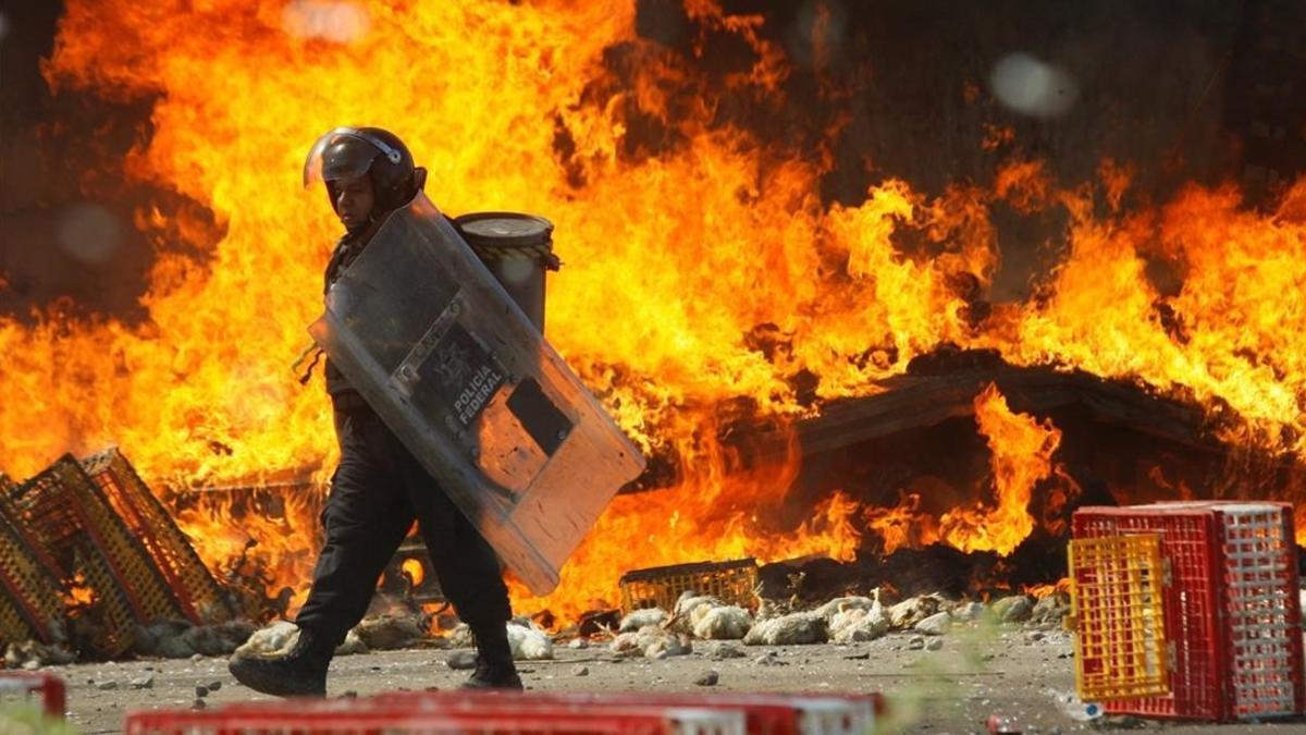 Un policía pasa frente a un camión en llamas durante las protestas contra la reforma educativa en Oaxaca.