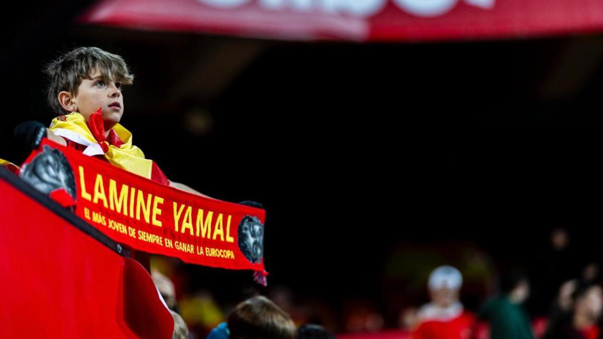 Un joven aficionado observa a los jugadores en Mestalla con una bufanda de Lamine Yamal