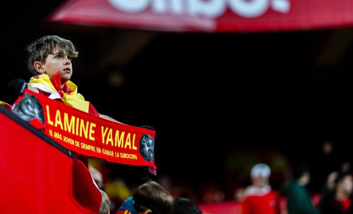 Un joven aficionado observa a los jugadores en Mestalla con una bufanda de Lamine Yamal