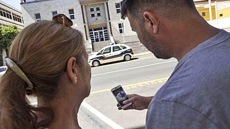 Jonatan Ruiz, junto a su madre, observa una fotografía de su hijo Dylan a través del móvil frente a los Juzgados.