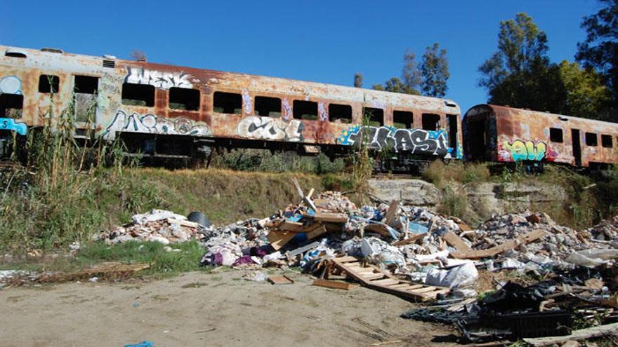 Vista de la escombrera ilegal junto a los vagones de tren abandonados.