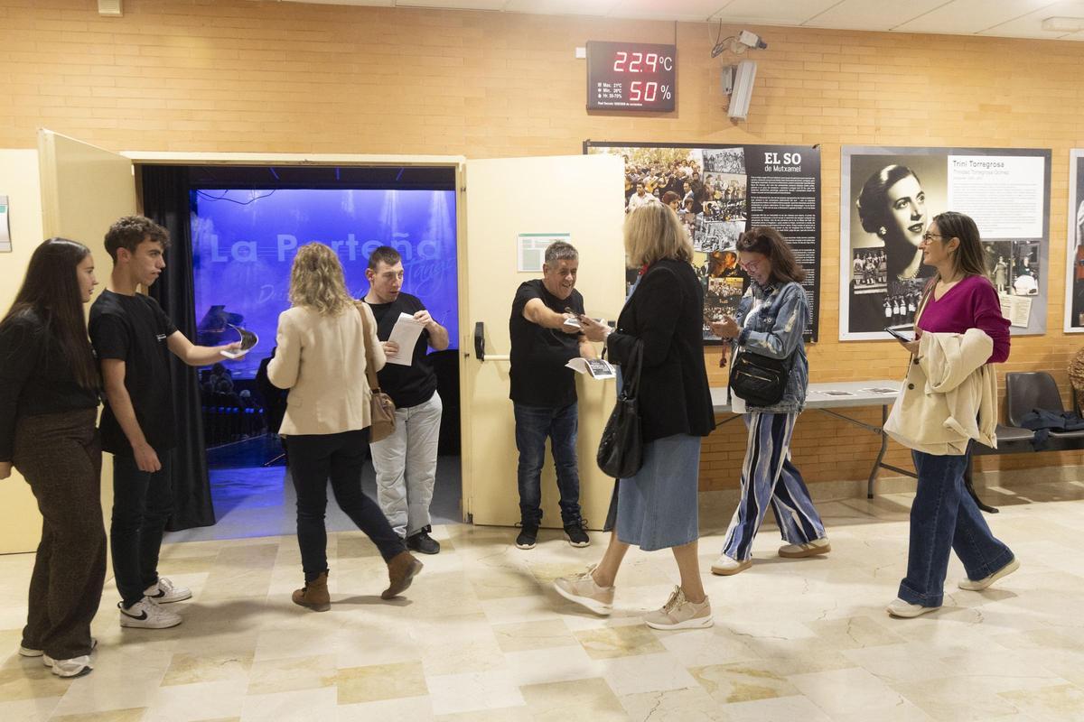 Tres de los voluntarios entregan folletos al público asistente a la actuación musical en Mutxamel