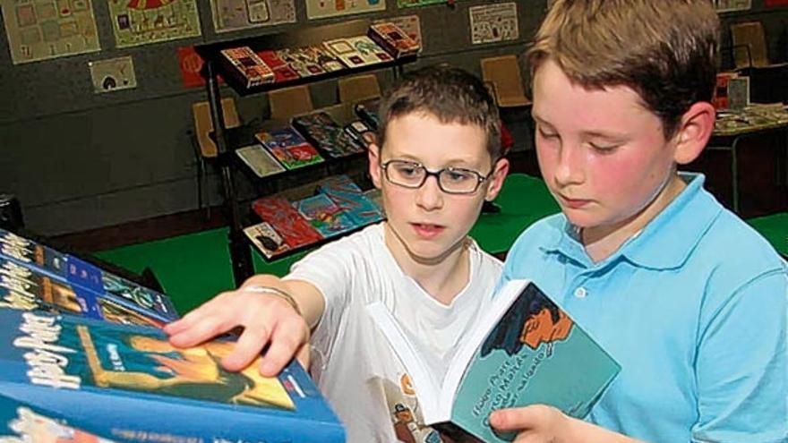 Dos niños consultan los libros que se presentan en la exposición.