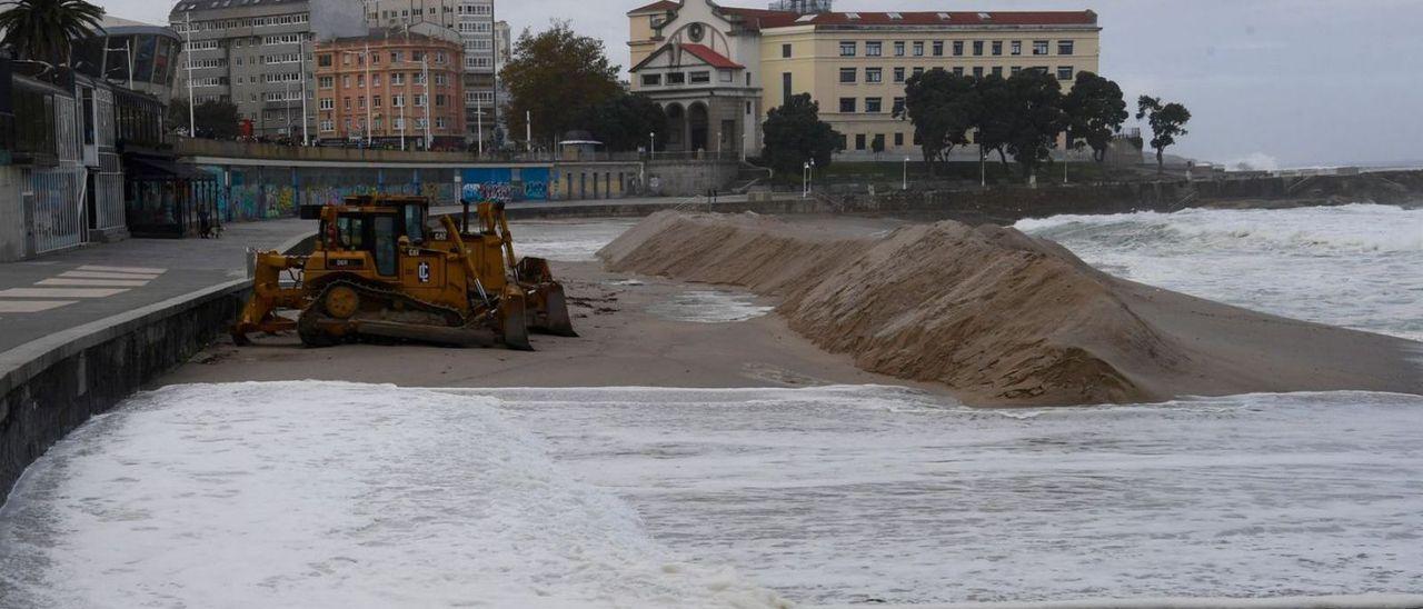 Olas superando la duna de protección levantada en la playa de Riazor (A Coruña).