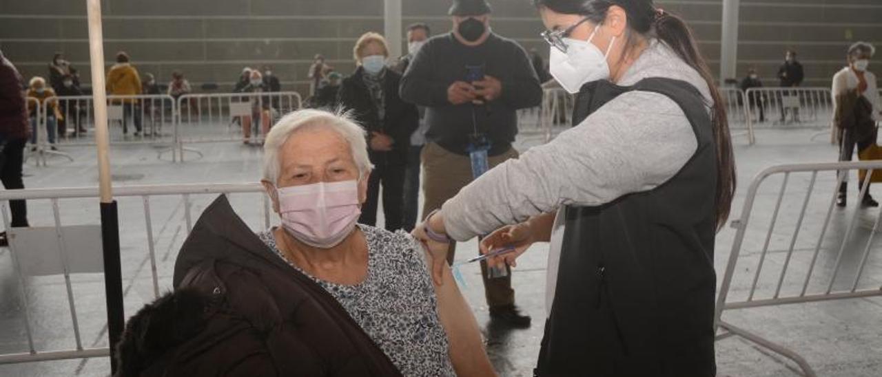 Una mujer recibe la dosis de Pfizer en la reanudación de la campaña de vacunación masiva en el Recinto Ferial.  | // RAFA VÁZQUEZ