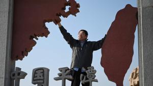Un hombre posa en una escultura que representa a China y Taiwán en la isla de Pingtan.