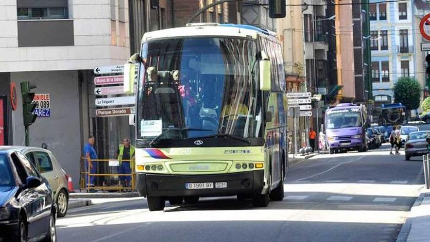 Tres buses de diversas líneas de transporte, en la calle Constitución de Sama.