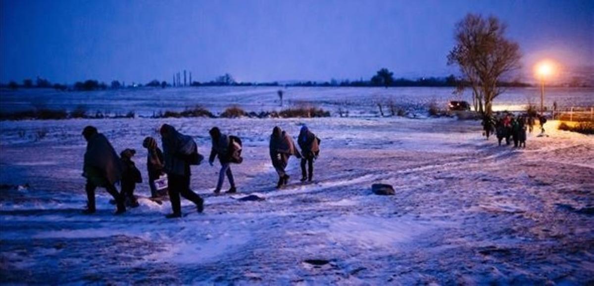 Migrantes y refugiados caminan por un campo cubierto de nieve tras cruzar la frontera de Macedonia con Serbia, cerca de la población de Miratovac, este domingo.