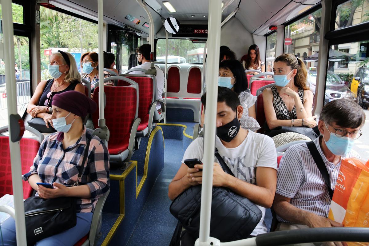 Viajeros con mascarilla en un bus.