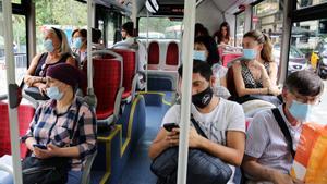 Viajeros con mascarilla en un bus.