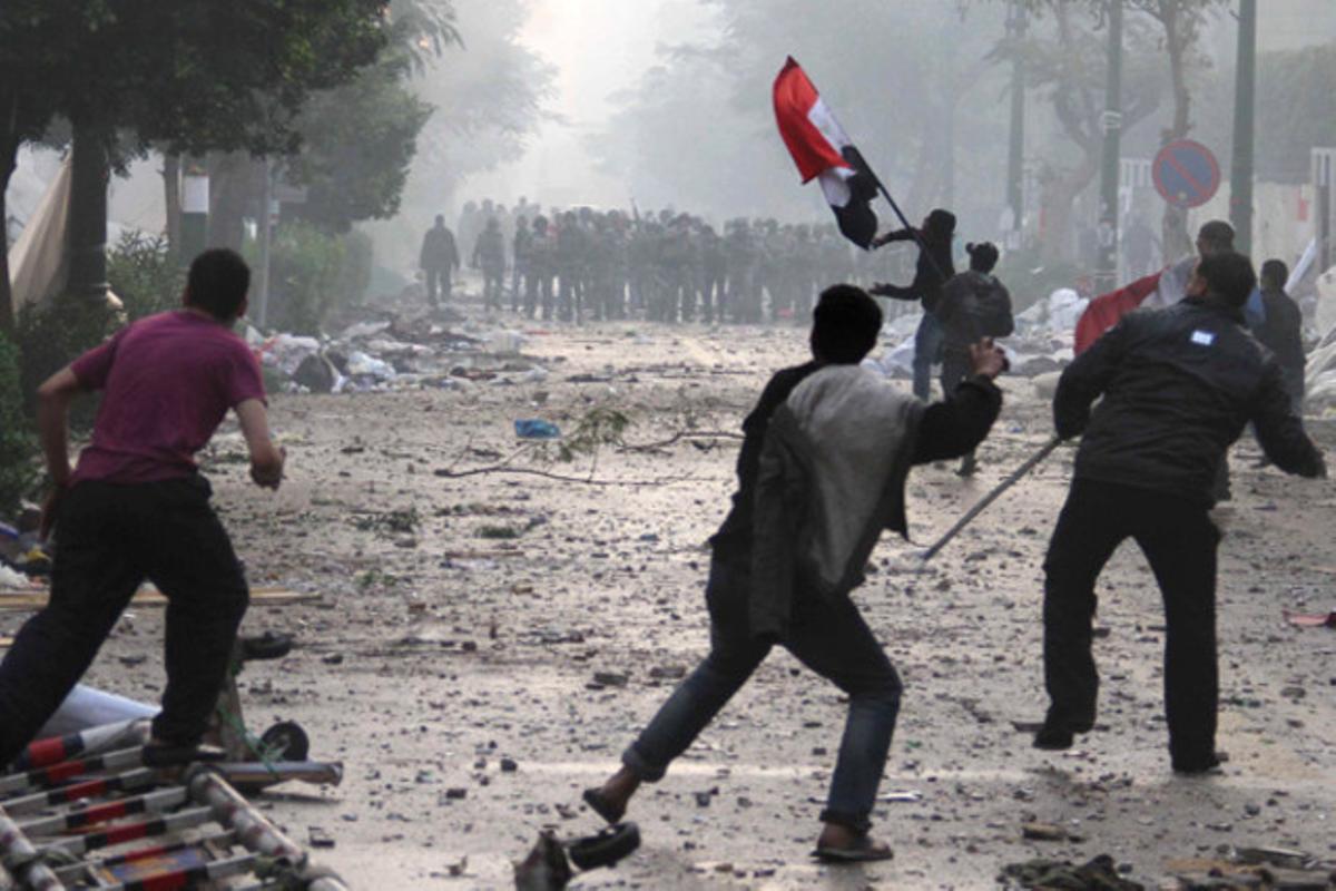 Joves egipcis llancen roques a la policia militar a prop de la plaça Tahrir, al Caire. Al·leguen que el conflicte el van començar els soldats a l’apallissar un jove manifestant.