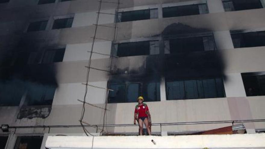 Un bombero intenta controlar el fuego de la fábrica textil.