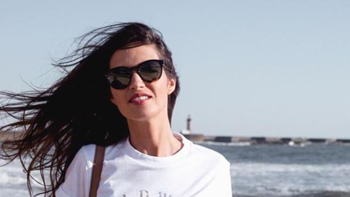 Sara Carbonero posando en la playa con vaqueros y camiseta blanca