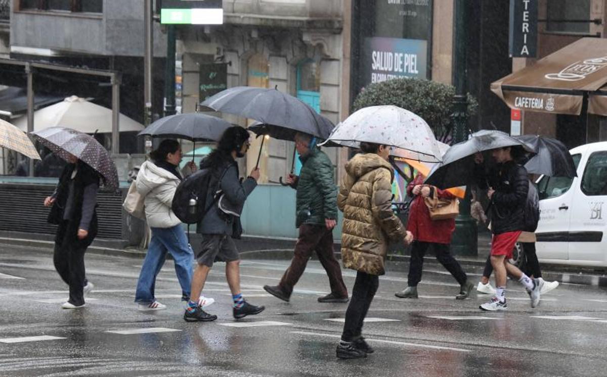 Gente con paraguas en la calle Urzáiz.