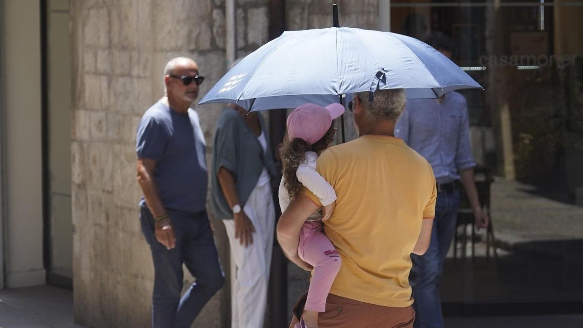 Dues persones protegint-se la calor amb un paraigües a Girona