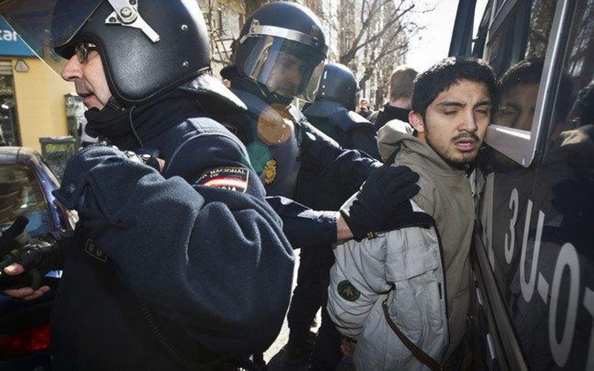 Un noi és emmanillat davant un furgó policial.