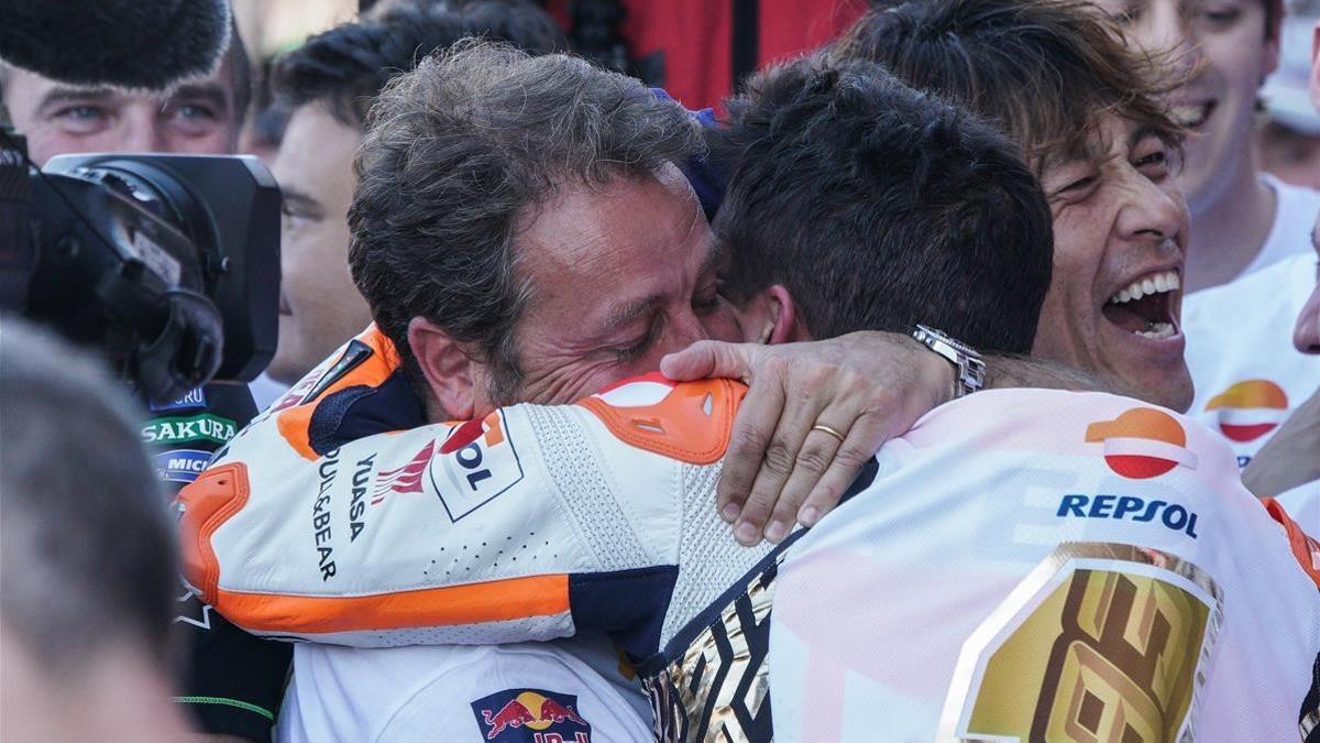 Emilio Alzamora, visiblemente emocionado, abraza y felicita a su pupilo, Marc Márquez, tras la conquista de su sexto título mundial de motociclismo en Valencia.