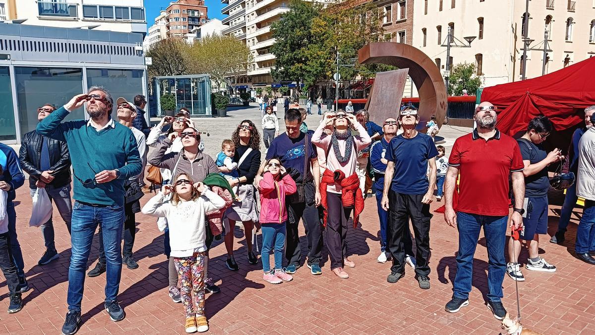 Varias personas observan el eclipse desde la plaza del Tirant, en Gandia.