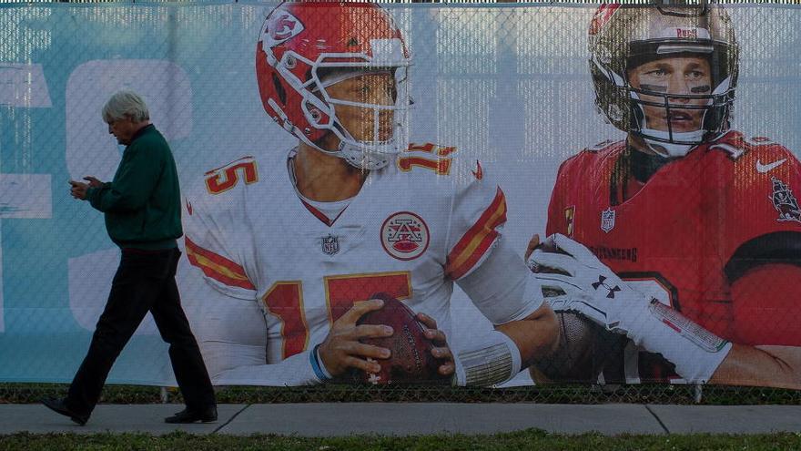 Un hombre camina junto a una valla con los retratos de Patrick Mahomes y Tom Brady.