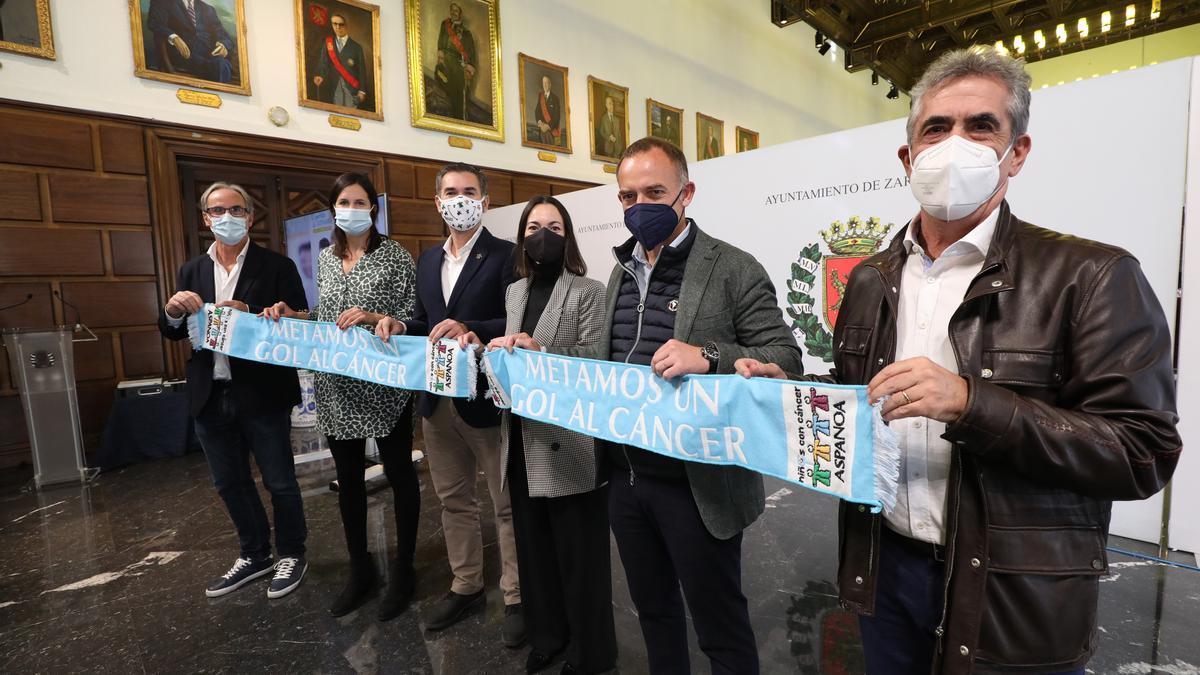 Representantes deportivos y políticos sostienen la bufanda promocional en la presentación del evento.