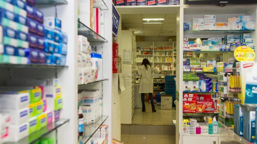 Una farmacéutica busca un medicamento en la trastienda de su botica.