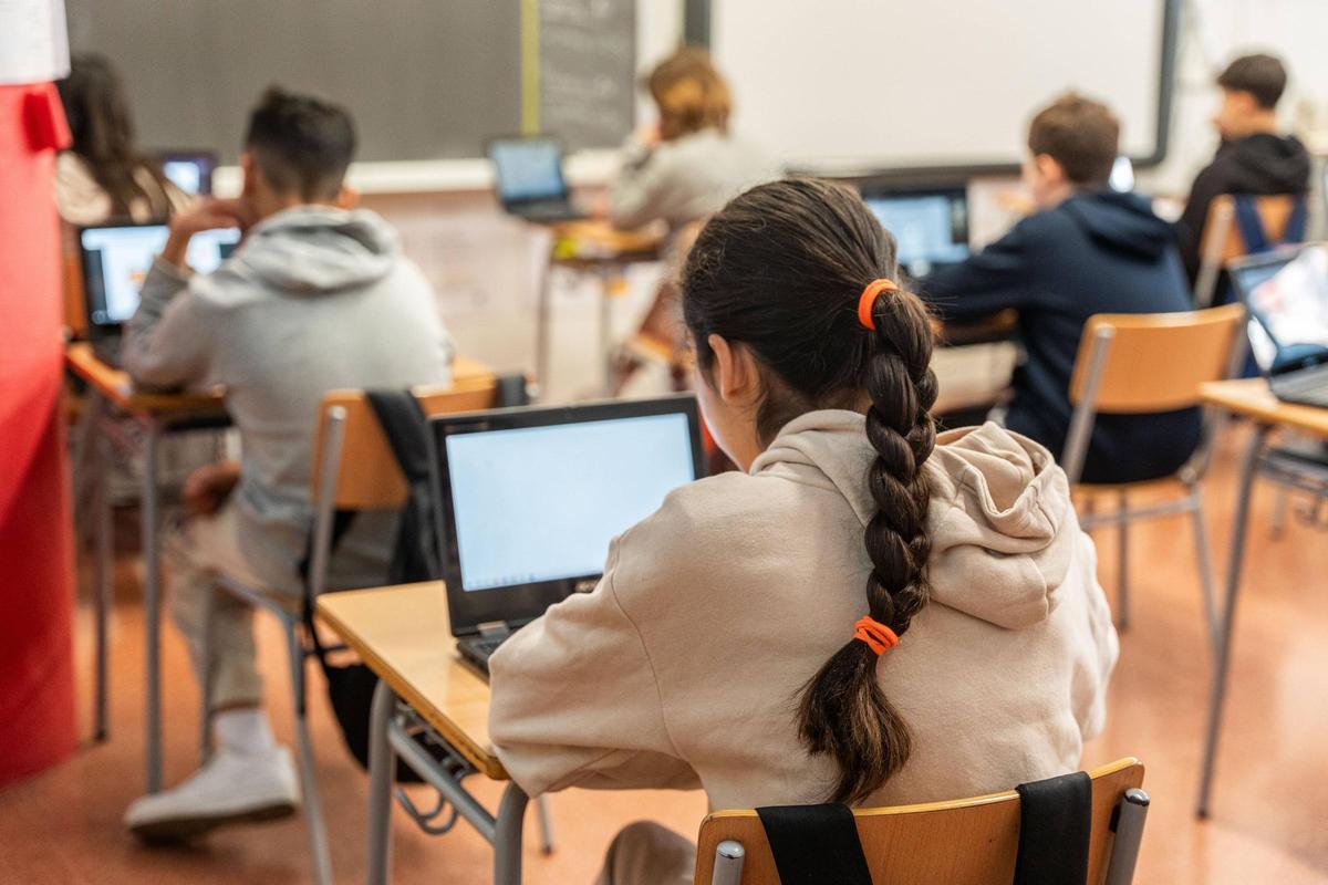 Un grupo de alumas y alumnos trabajan en clase con sus ordenadores, en un instituto.