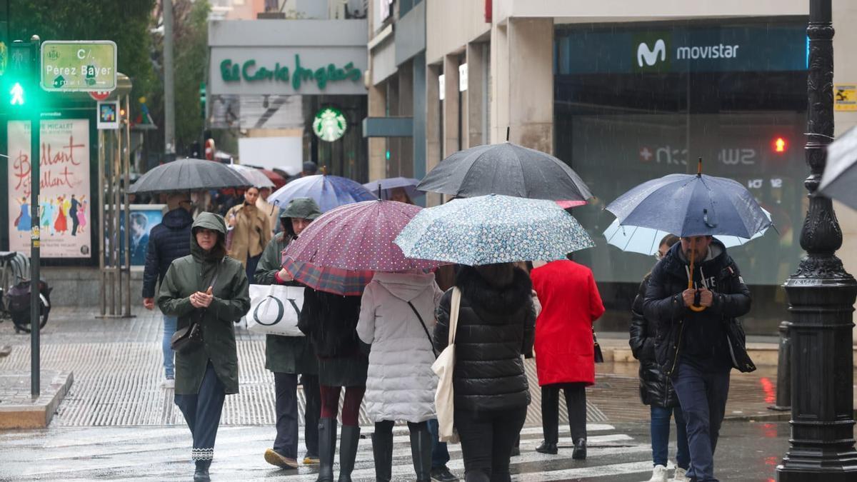 Varias personas caminan bajo la lluvia en Valencia, este domingo.
